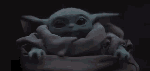 a baby yoda is sitting in a blanket in the dark .