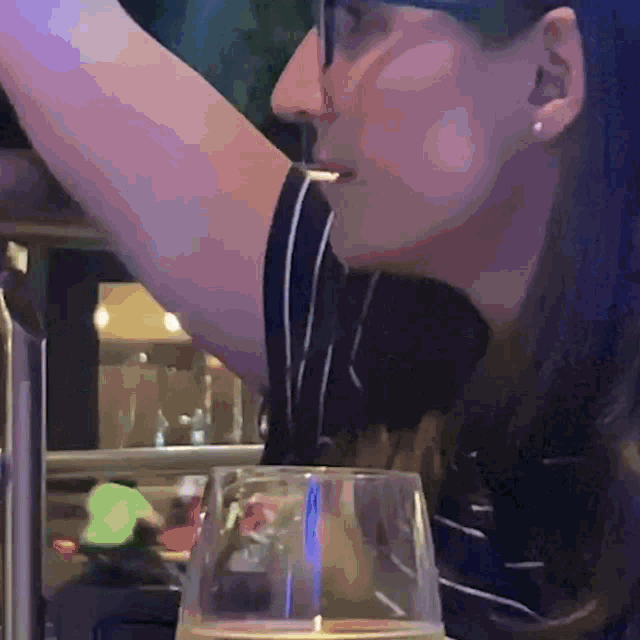 a woman with blue hair is drinking from a glass in a restaurant