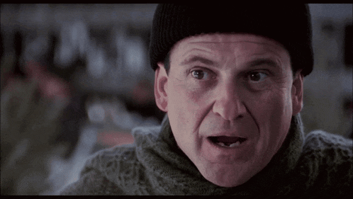 a man wearing a beanie and a sweater looks at the camera