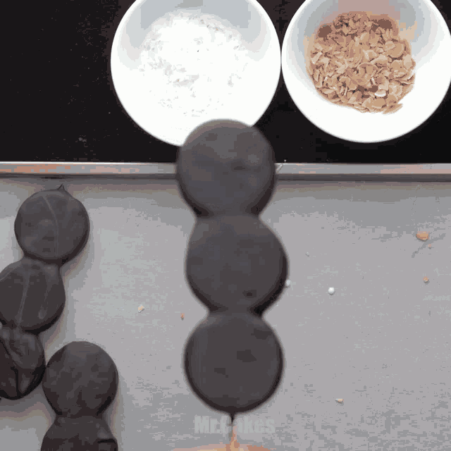 a person is holding a stack of oreos on a stick in front of bowls of ingredients including powdered sugar