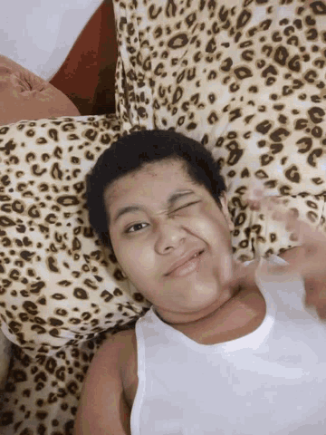 a young boy laying on a bed with a leopard print blanket
