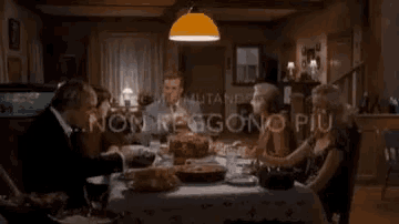 a group of people are sitting at a table with food and talking .