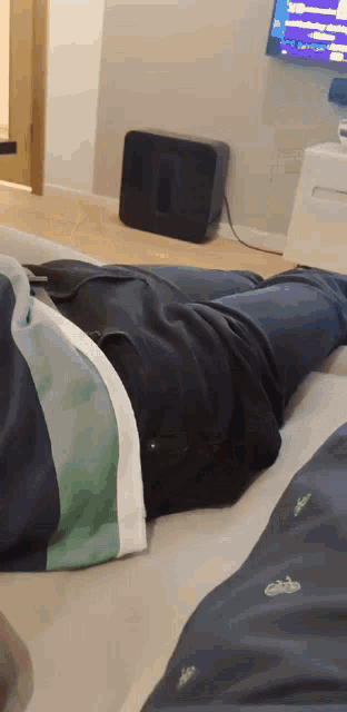 a person laying on a bed with their legs crossed in front of a tv