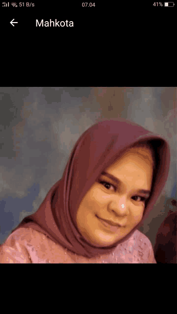 a woman wearing a purple head scarf is displayed on a phone screen