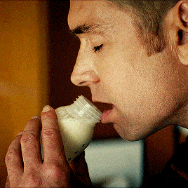 a man is drinking milk from a bottle that says ' aa ' on the side