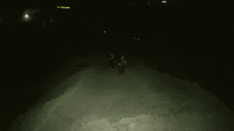 two people are running down a dirt road at night .