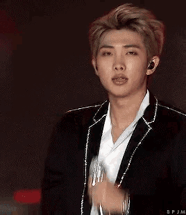 a young man wearing a black jacket and white shirt is holding a microphone .
