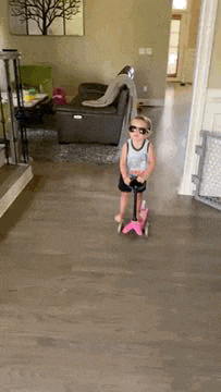 a little boy is riding a scooter in a living room .