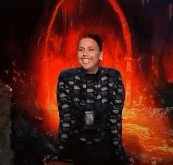 a woman is sitting in a cave with her mouth open in front of a fire .