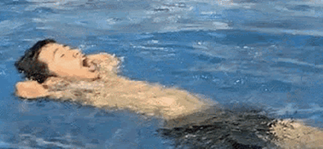 a man is laying on his back in a swimming pool .