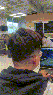a man wearing glasses is typing on a laptop computer
