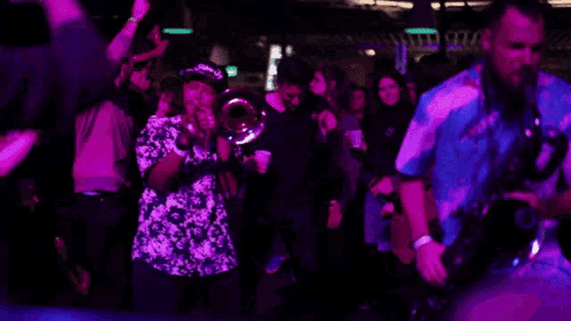 a man playing a saxophone in front of a crowd with a purple background
