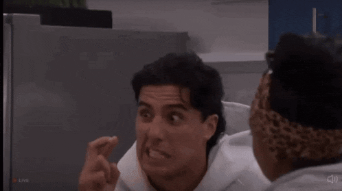 a man in a white hoodie is making a funny face while talking to another man in a grey hoodie .