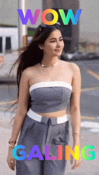 a woman in a gray top and pants is walking down a street with the words wow galing behind her