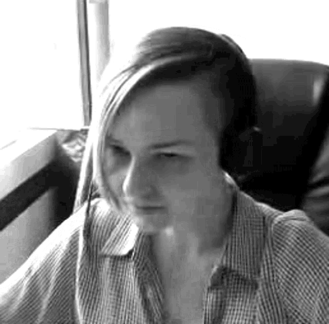 a woman wearing headphones is sitting in a chair in front of a window in a black and white photo .