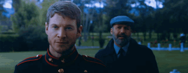 a man in a military uniform stands next to another man with a beard