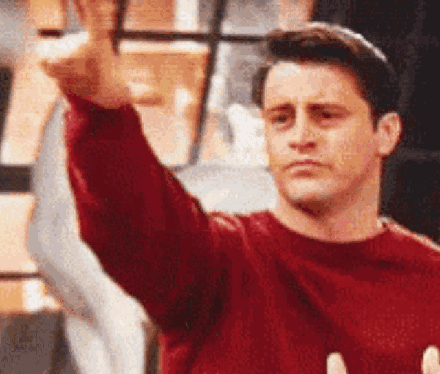 a man wearing a red sweater is giving a thumbs up .