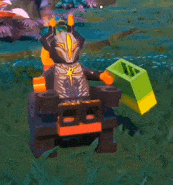 a lego figure is standing in the grass holding a green cube .