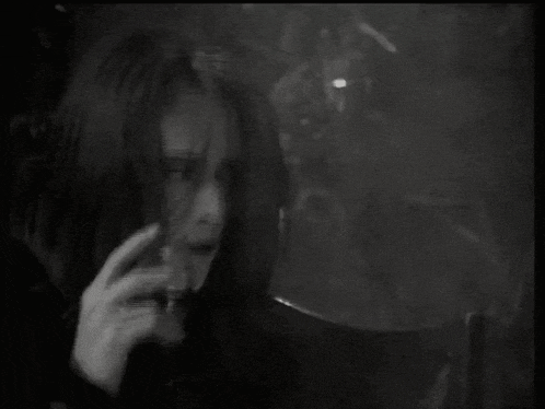 a black and white photo of a woman smoking a cigarette .