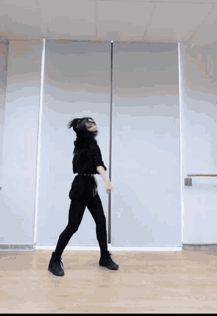 a woman in a black outfit is dancing in a dance studio