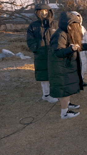 a woman in a black coat with a hood on her head is pointing