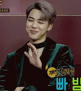 a young man wearing a green jacket and a choker is waving his hand