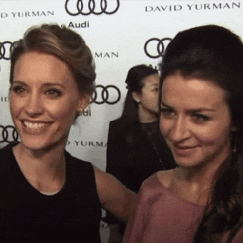 two women are posing for a photo in front of a david yurman sign
