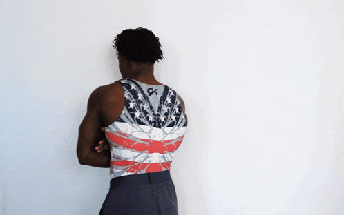 a man with his arms crossed wears a tank top with the letter gk on the back