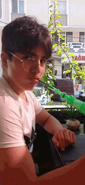 a young man wearing glasses and a white shirt is playing with a green squirt gun