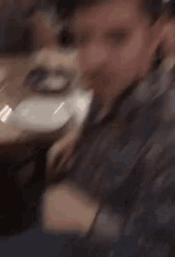 a man in a blue shirt is sitting at a table with plates on it .