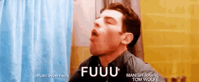 a man is yawning in a bathroom next to a shower curtain and a blue towel .
