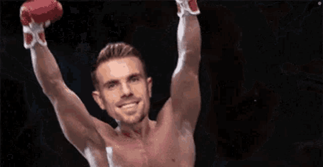 a shirtless boxer is holding his arms in the air and smiling .