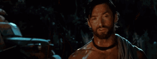 a man without a shirt is taking off his belt and holding a toothbrush .