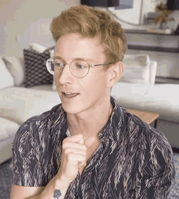 a man wearing glasses and a shirt with a tattoo on his arm