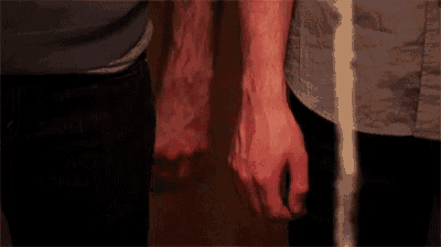 two men are holding hands in a room .