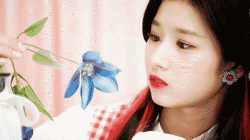a close up of a woman holding a blue flower .