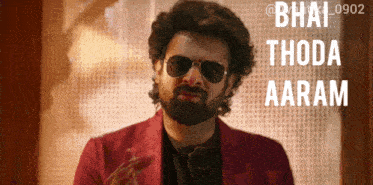 a man wearing sunglasses and a red jacket says " bhai thoda aaram " on the bottom