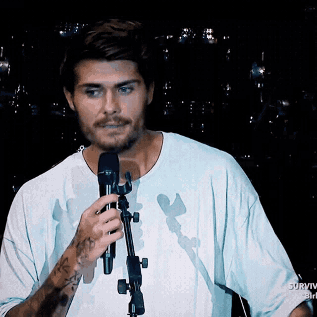a man in a white shirt is holding a microphone with survivor on the bottom right