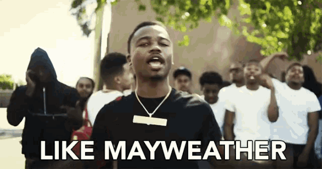 a man in a black shirt stands in front of a crowd with the words like mayweather below him
