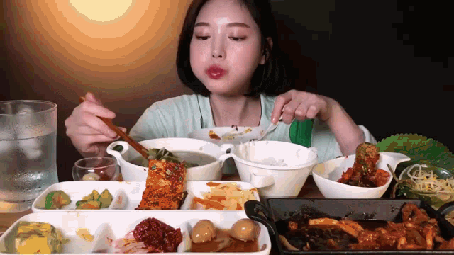 a woman is sitting at a table eating a variety of food