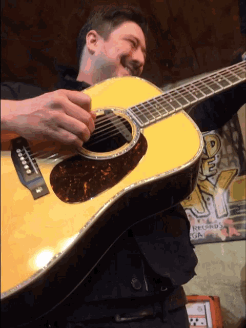 a man is playing an acoustic guitar in front of a sign that says records