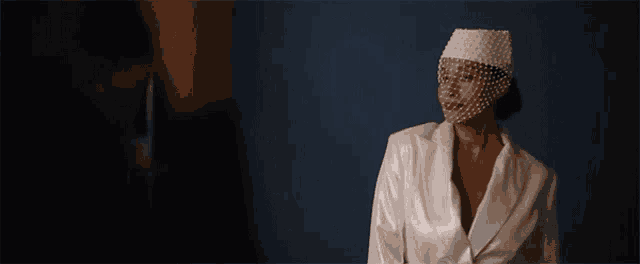 a woman in a suit is standing in front of a microphone in a dark room .