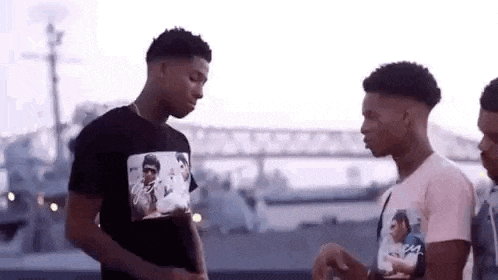 three young men are standing next to each other in front of a body of water .