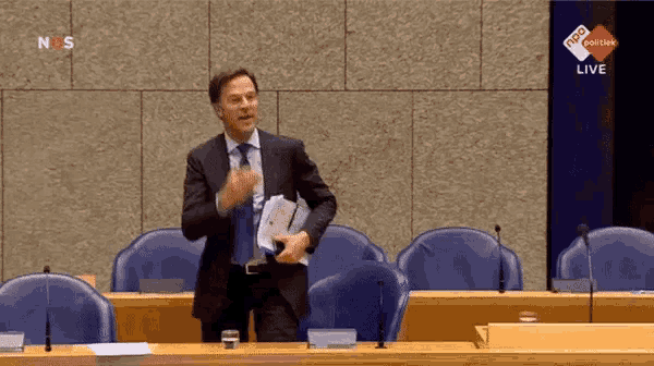 a man in a suit and tie stands in front of a screen that says ns live