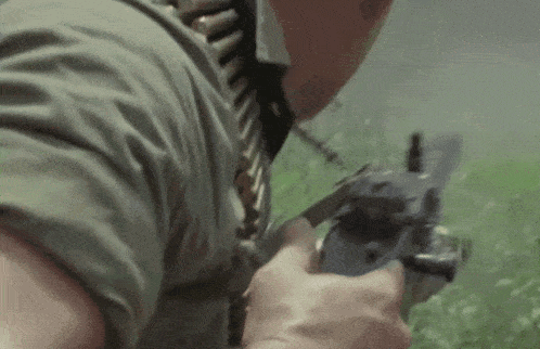 a man in a green shirt is holding a gun in his hands