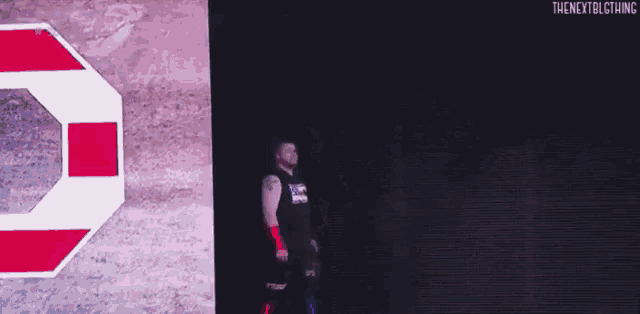 a man is walking on a stage in front of a large screen with a stop sign on it .