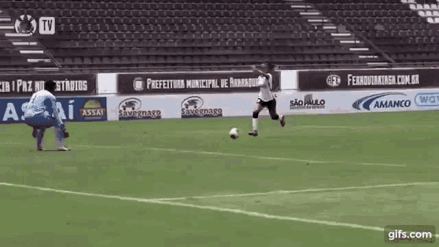 a soccer player is kicking a ball on a field with advertisements for prefeitura municipal de araraquara