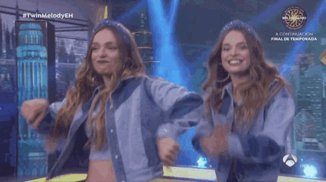 two women are dancing on a stage in front of a millionaire show