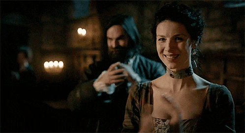 a man and a woman are standing next to each other in a dark room and the woman is smiling