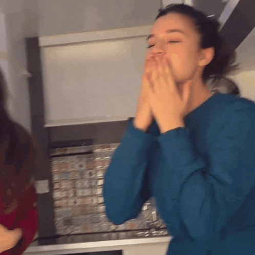 a woman covering her mouth with her hands in a kitchen